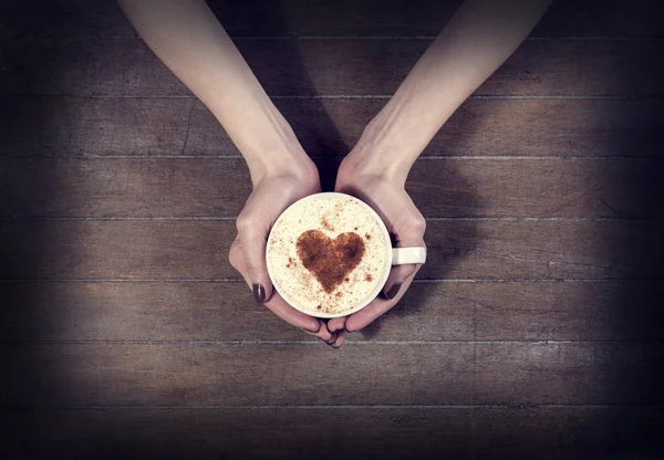 Mulher segurando xícara quente de café, com forma de coração — Fotografia de Stock