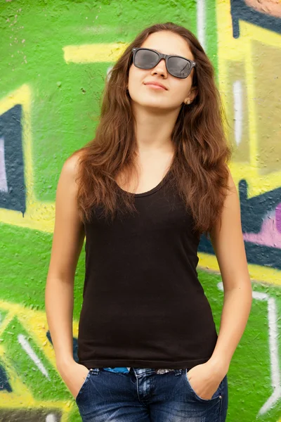 Style teen girl dans des lunettes de soleil près de fond de graffiti . — Photo