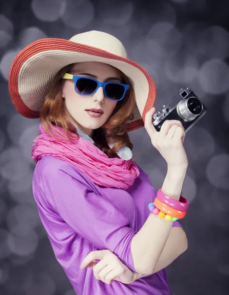Legrační rusovláska dívka v klobouku s kamerou a bokeh na pozadí — Stock fotografie