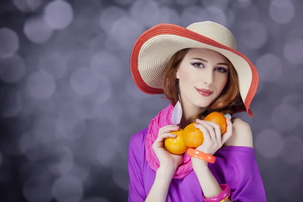 Beautiful red-haired girl with oranges at bokeh background — Stock Photo, Image