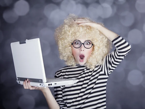 Portret van grappig meisje in blonde pruik met laptop. studio opname. — Stockfoto