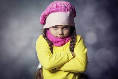 Close-up portrait of adorable sad child girl wearing pink knitte