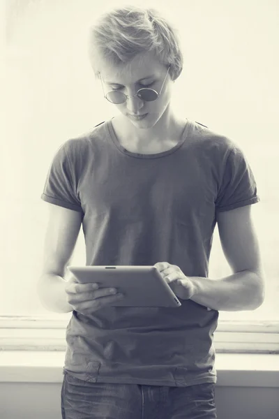 Ragazzo hipster con tablet vicino alla finestra. Foto con un po 'di rumore — Foto Stock