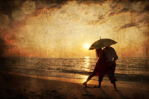 Couple kissing under umbrella at the beach in sunset. Photo in o — Stock Photo, Image