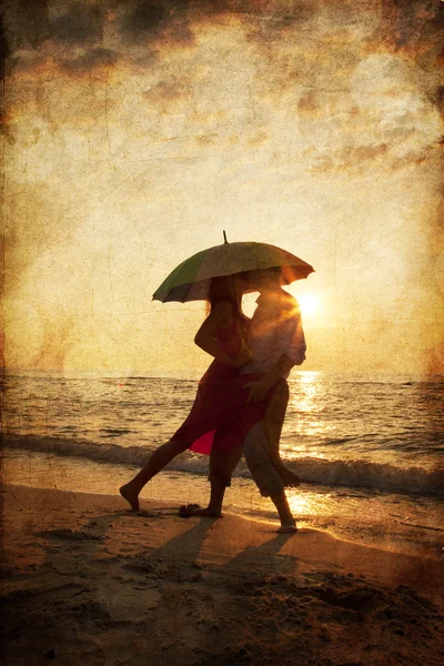 Couple kissing under umbrella at the beach in sunset. Photo in o — Stock Photo, Image