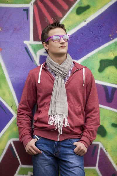 Stijl tiener jongen in de buurt van graffiti achtergrond. — Stockfoto