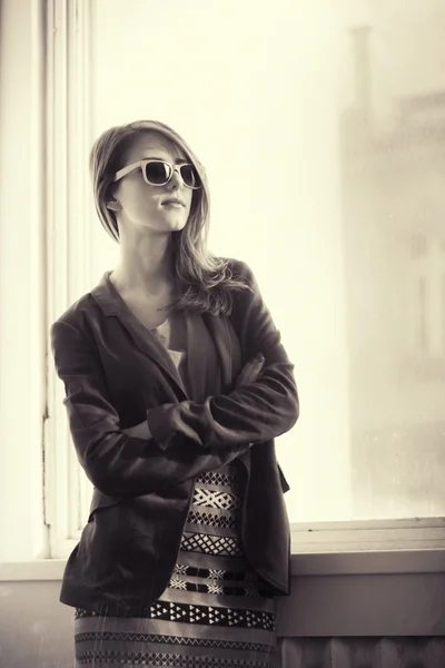 Girl in sunglasses near window — Stock Photo, Image