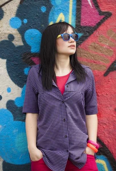 Stile teen ragazza in piedi vicino muro graffiti . — Foto Stock
