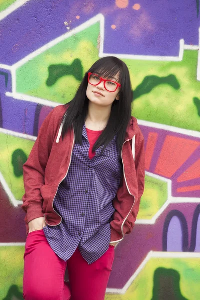 Styl dospívající dívka stojící poblíž graffiti zeď. — Stock fotografie