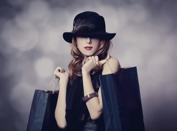 Stijl roodharige meisje met shopping tassen. — Stockfoto