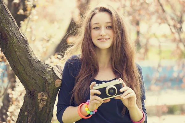 Teen girl in glasses with vintage camera near blossom tree — Stock Photo, Image