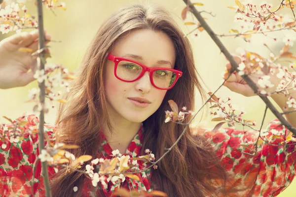 Ragazza adolescente in occhiali vicino albero di fiori — Foto Stock