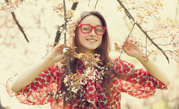 Adolescente chica en gafas cerca de árbol de flores — Foto de Stock