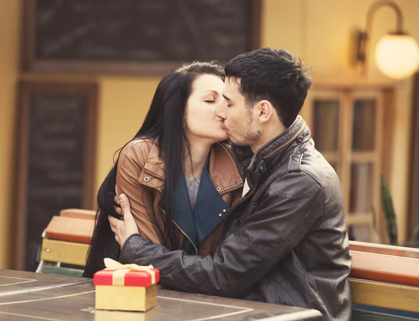 El joven le da un regalo a una joven en el café y ellos —  Fotos de Stock