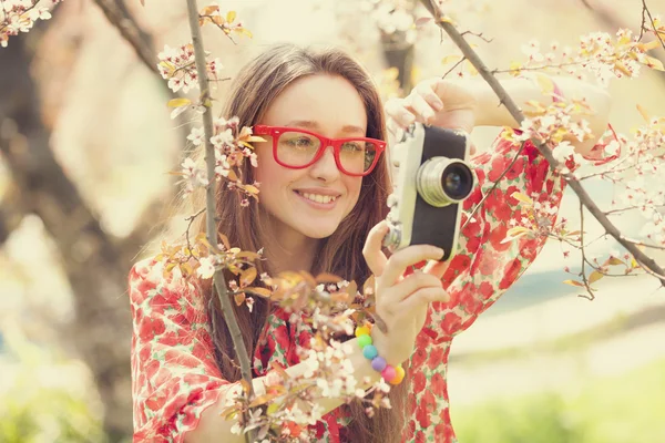 Adolescent fille dans lunettes avec vintage caméra près de floraison arbre — Photo