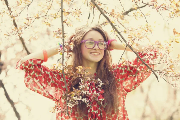 Девочка в очках рядом с цветущим деревом — стоковое фото