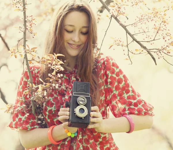 Teen girl in glasses with vintage camera near blossom tree — Stock Photo, Image