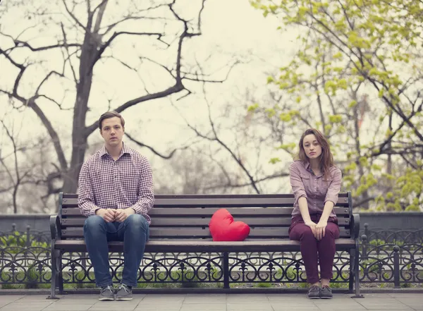 Sad teens sitting at the bench at the park — Stock Photo, Image