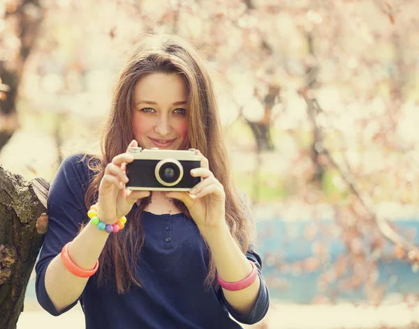 Chica adolescente en gafas con cámara vintage cerca de árbol de flores —  Fotos de Stock