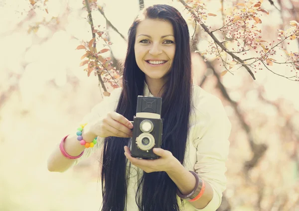 Beautiful girl with camera in spring park — Stock Photo, Image