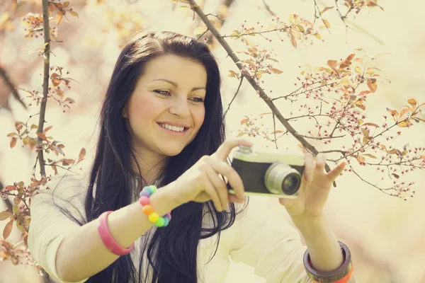 Mooi meisje met camera in voorjaar park — Stockfoto