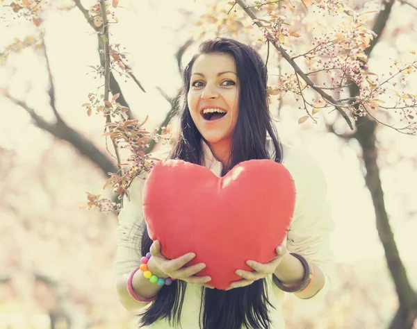Mooi meisje met speelgoed hart in voorjaar park — Stockfoto