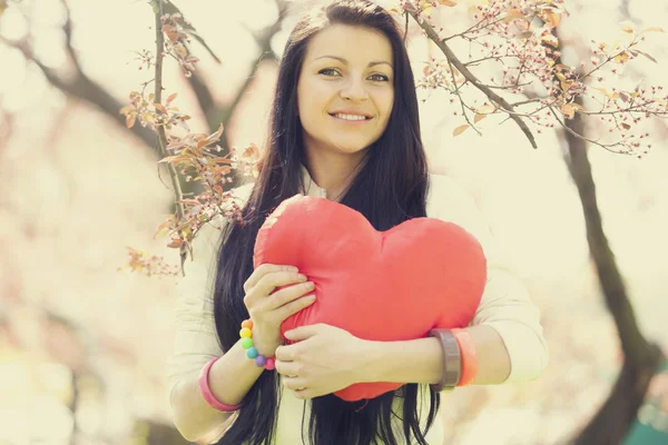 Beautiful girl with toy heart in spring park — Stock Photo, Image