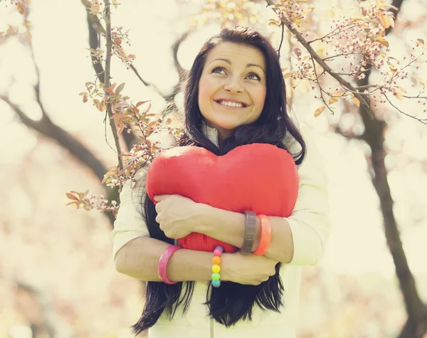 Beautiful girl with toy heart in spring park Stock Picture