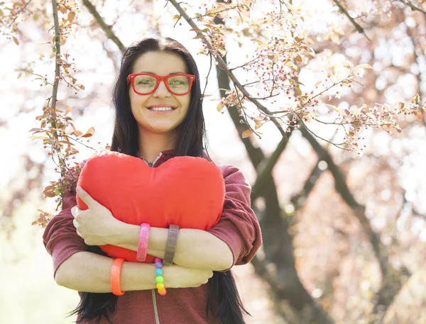 Красива дівчина з іграшковим серцем у весняному парку — стокове фото