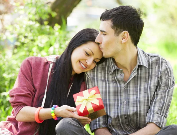 Couple with gift at green grass in the park — Stock Photo, Image