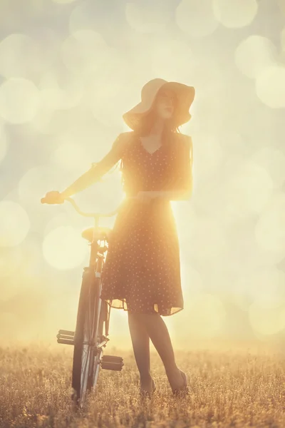 Menina e em uma bicicleta no campo ao nascer do sol — Fotografia de Stock