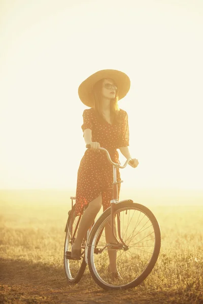 Chica en una bicicleta en el campo en el amanecer — Foto de Stock