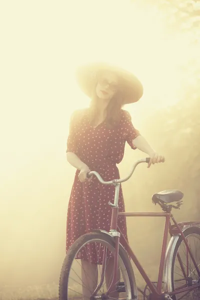 Chica en una bicicleta en el campo en el amanecer —  Fotos de Stock