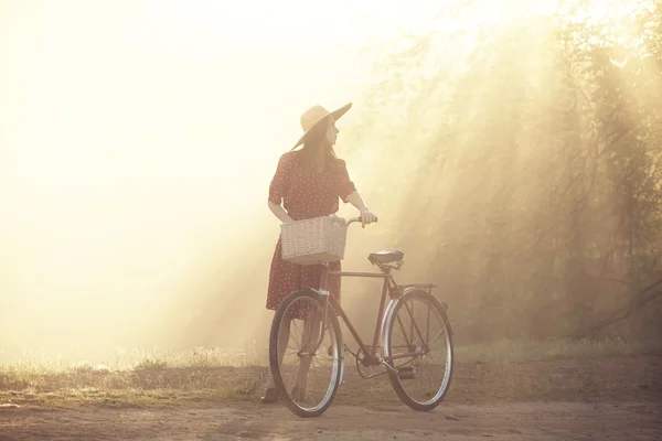 Menina de bicicleta no campo na hora do nascer do sol — Fotografia de Stock