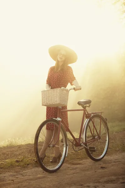 Chica en una bicicleta en el campo en el amanecer —  Fotos de Stock