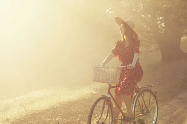 Menina de bicicleta no campo na hora do nascer do sol — Fotografia de Stock