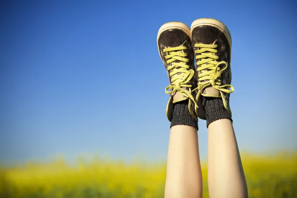 Vintage zapatillas de deporte descansando en el cielo azul y campo de colza backgroun — Foto de Stock