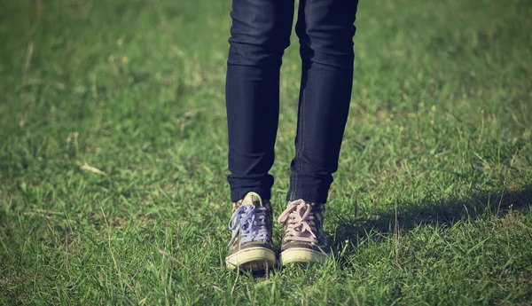 Girl in vintage sneakers resting on the grass — Stock Photo, Image