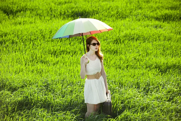 Redhead enchantress with umbrella and suitcase at spring country — Stok fotoğraf