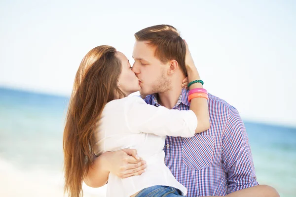 Porträtt av ung man och kvinna kysser på en strand — Stockfoto