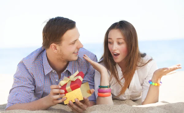 Retrato de hombre y mujer joven con regalo en una playa . — Foto de Stock