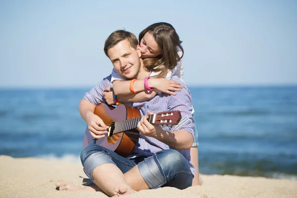 Portrait de jeune homme avec guitare et femme sur une plage — Photo