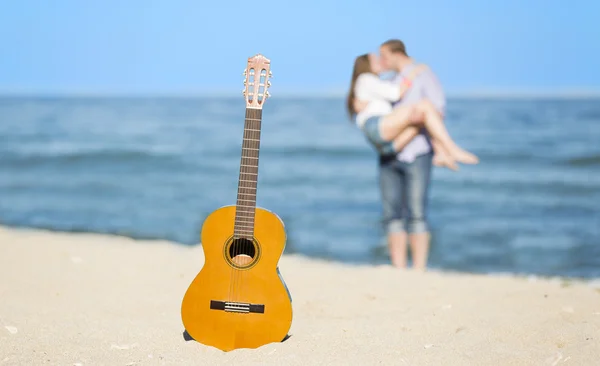 Retrato de hombre y mujer jóvenes en una playa y guitarra — Foto de Stock