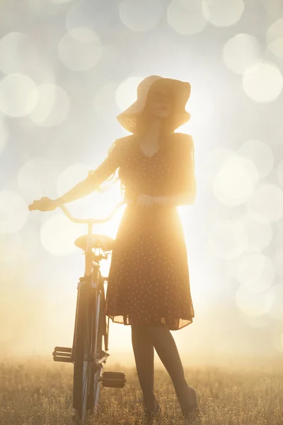 Menina de bicicleta no campo na hora do nascer do sol — Fotografia de Stock