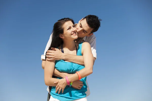 美丽的夫妇在蓝蓝的天空背景上接吻 — 图库照片