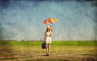 Redhead enchantress with umbrella and suitcase at spring country