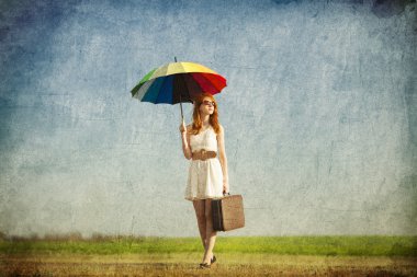 Redhead enchantress with umbrella and suitcase at spring country