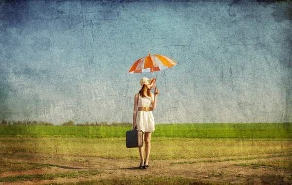 Rothaarige Zauberin mit Regenschirm und Koffer im Frühlingsland — Stockfoto