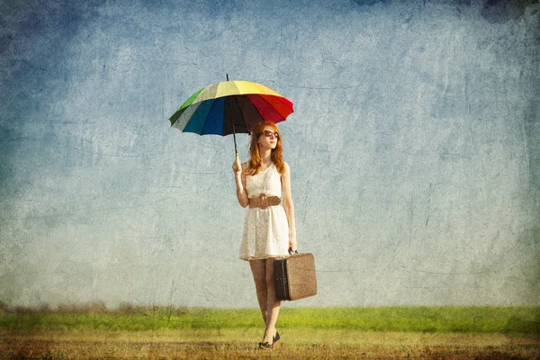 Rothaarige Zauberin mit Regenschirm und Koffer im Frühlingsland — Stockfoto