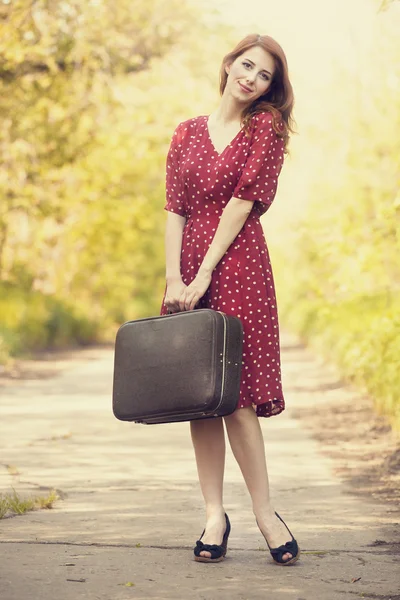 Ragazza rossa con valigia nel vicolo dell'albero . — Foto Stock